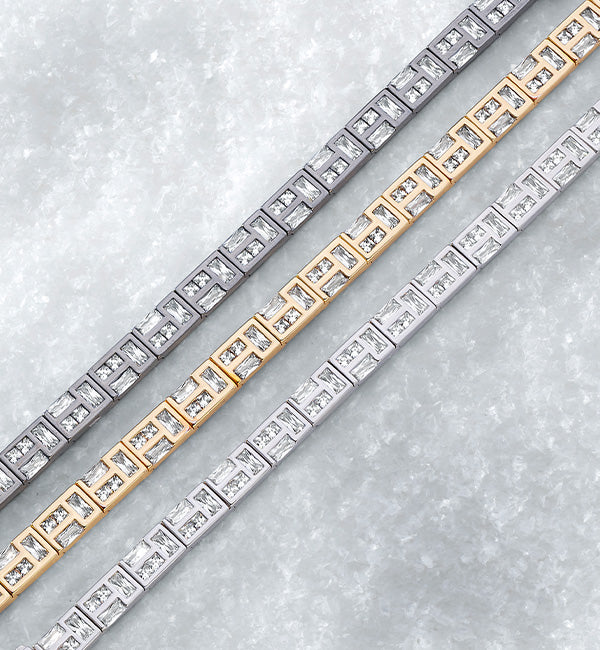 Three APM MONACO bracelets in yellow gold, silver, and dark silver on a light gray background