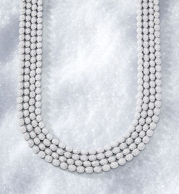 Multiple strands of APM MONACO silver beaded necklace on a textured gray background