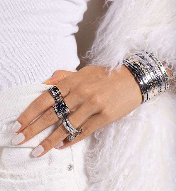Hand wearing multiple APM MONACO silver rings and bracelets from morse code collection 